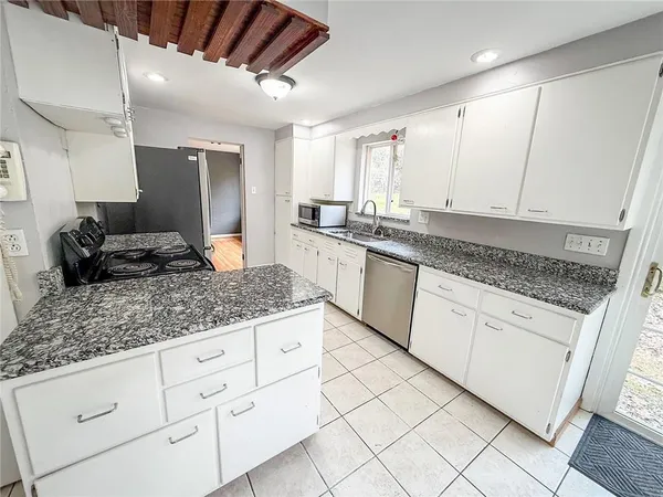 a kitchen with granite countertop white cabinets white appliances and granite counter tops