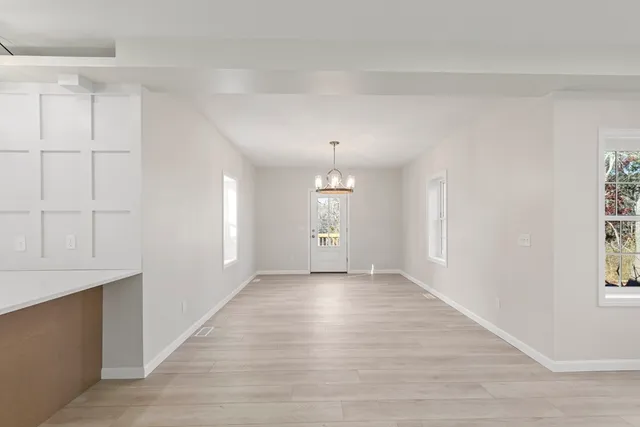 a view of an empty room with window and wooden floor