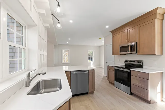 a kitchen with granite countertop a sink wooden cabinets and stainless steel appliances