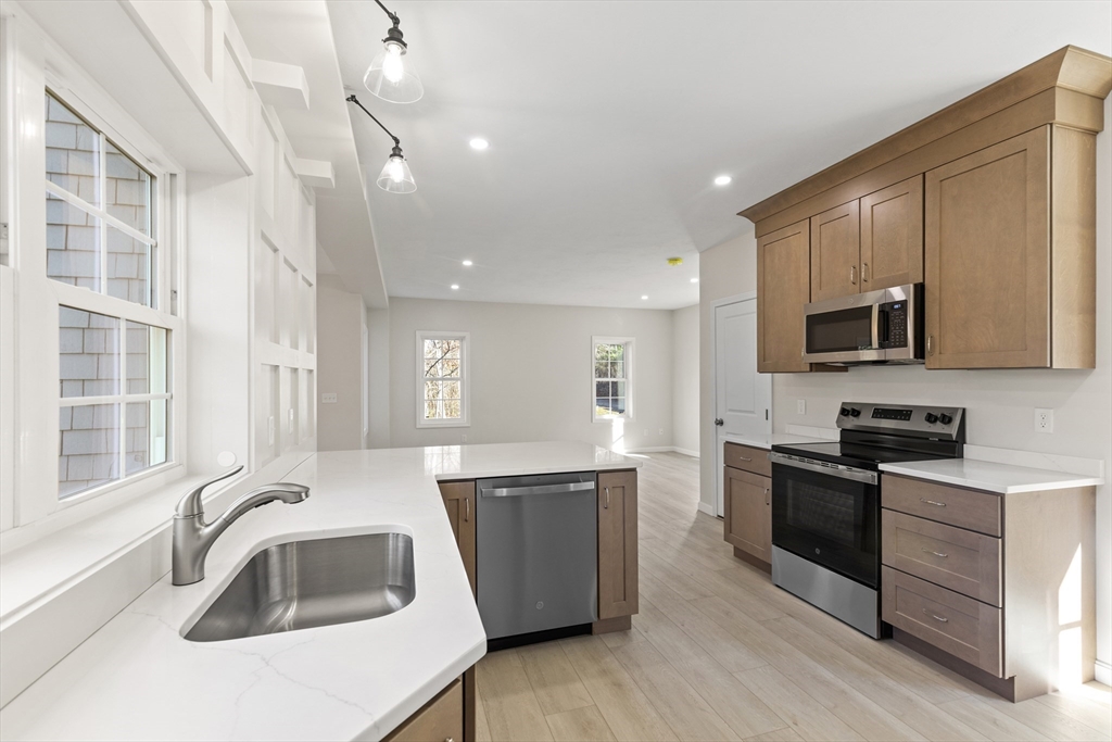 1234 State Road, Unit 1 Plymouth, MA 02360 - Photo 6 of 32 a kitchen with granite countertop a sink wooden cabinets and stainless steel appliances