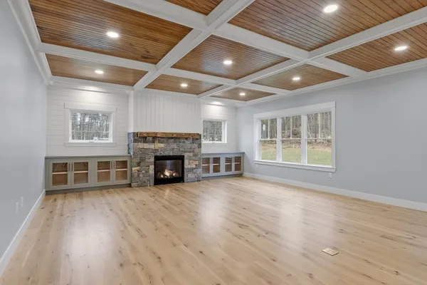 a view of an empty room with wooden floor fireplace and a window