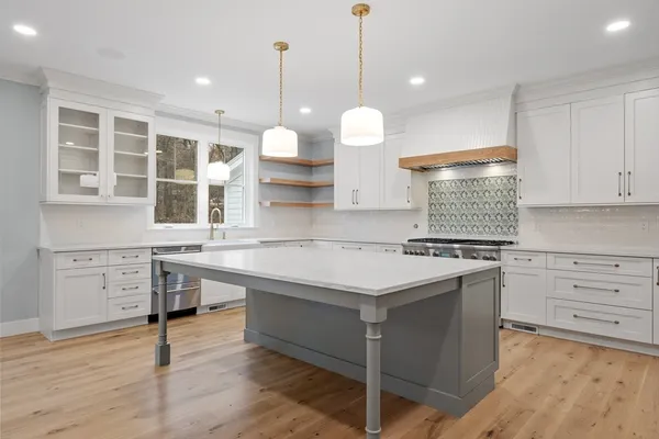 a kitchen with a stove a sink and wooden floor