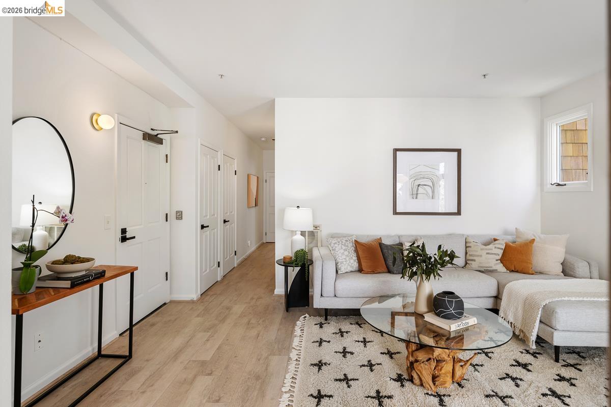 2029 Channing Way, Unit 3D Berkeley, CA 94704 - Photo 25 of 54 Bright living space featuring light wood-finish flooring, white walls, multiple interior doors with matte black hardware, and a window with wood siding visible