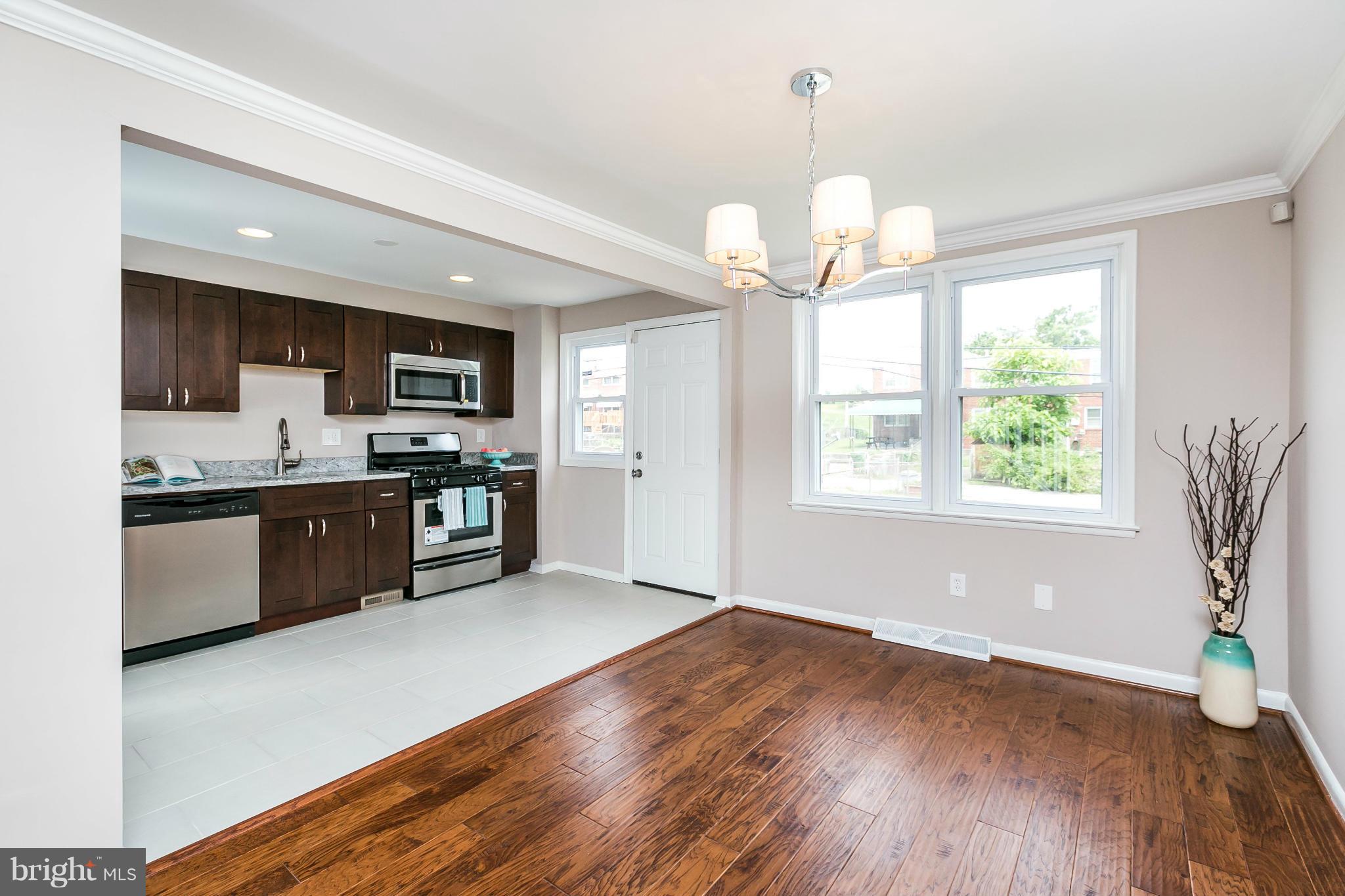 5417 Bucknell Road Baltimore, MD 21206 - Photo 11 of 30 a large kitchen with stainless steel appliances granite countertop a stove top oven a sink dishwasher a dining table and chairs with wooden floor