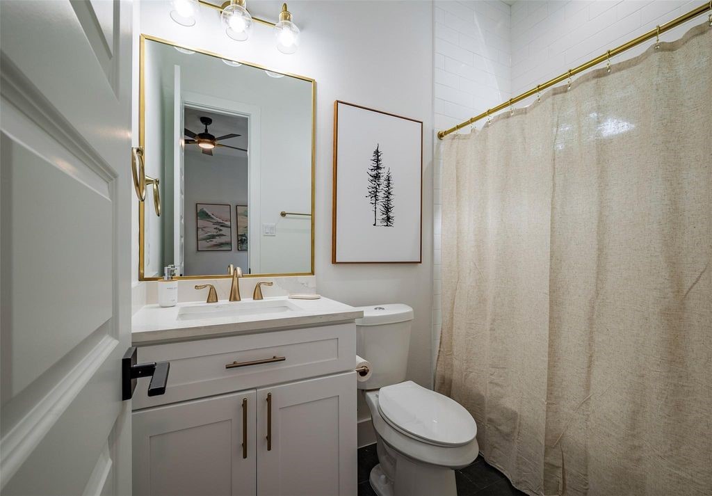 1305 East 27th Street, Unit B Houston, TX 77009 - Photo 18 of 27 a bathroom with a sink a toilet a mirror and shower curtain