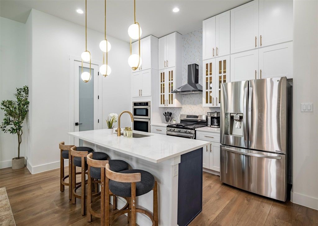 1305 East 27th Street, Unit B Houston, TX 77009 - Photo 8 of 27 a kitchen with granite countertop a refrigerator a stove a dining table and chairs with wooden floor