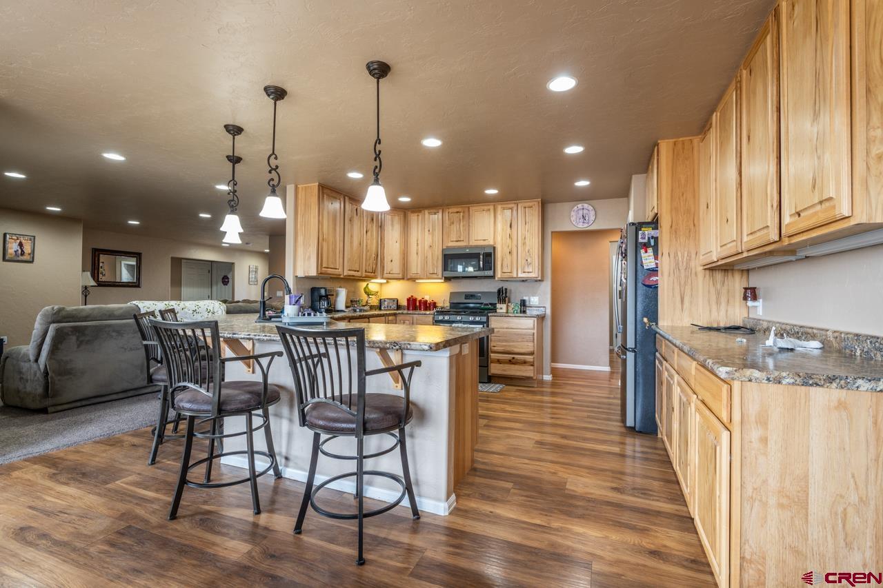 1265 H25 Road Delta, CO 81416 - Photo 18 of 34 a kitchen with stainless steel appliances kitchen island granite countertop a stove a refrigerator a kitchen island a dining table and chairs with wooden floor