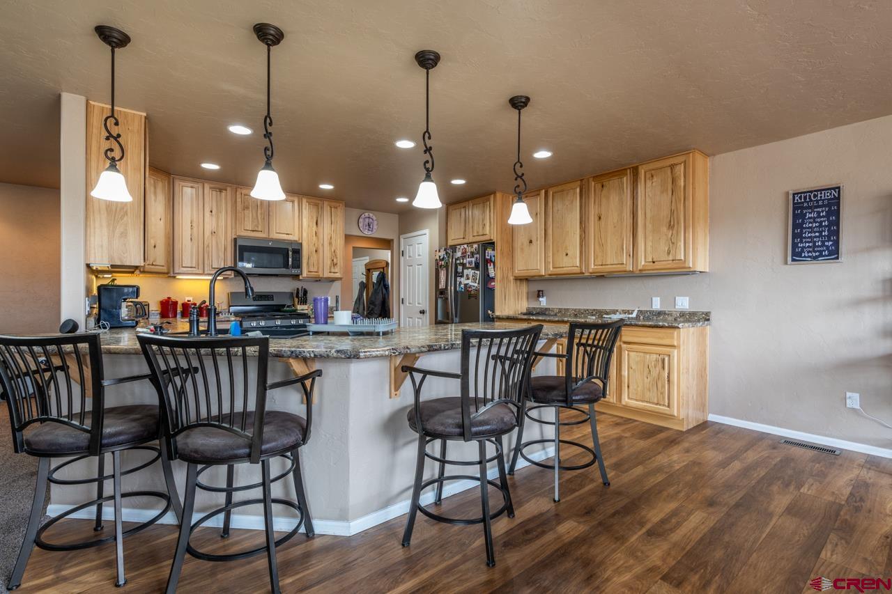 1265 H25 Road Delta, CO 81416 - Photo 19 of 34 a kitchen with stainless steel appliances granite countertop a stove a kitchen island a dining table and chairs with wooden floor