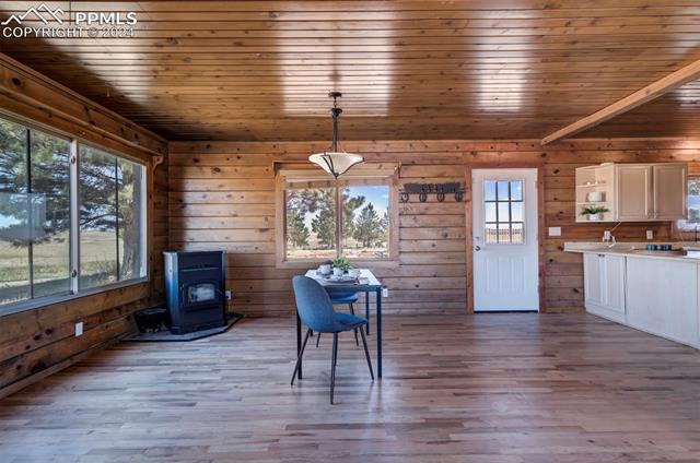 19350 Lemesany Road Calhan, CO 80808 - Photo 17 of 46 Dining room featuring a pellet stove, wood-style floors, and plenty of natural light