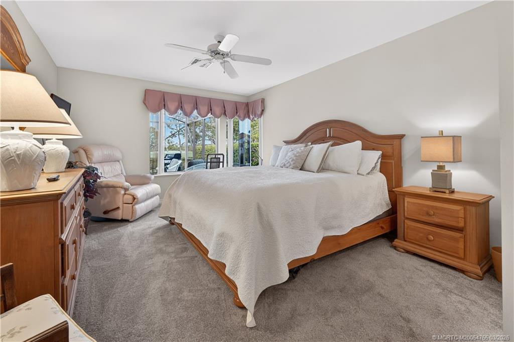 13319 Northwest Maplewood Road Palm City, FL 34990 - Photo 25 of 42 a bedroom with a bed and a chandelier