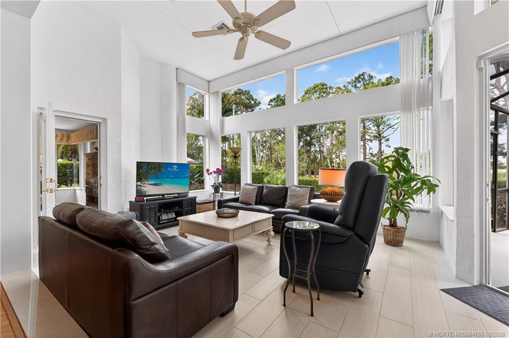 13319 Northwest Maplewood Road Palm City, FL 34990 - Photo 6 of 42 a living room with furniture potted plant floor to ceiling windows and a flat screen tv