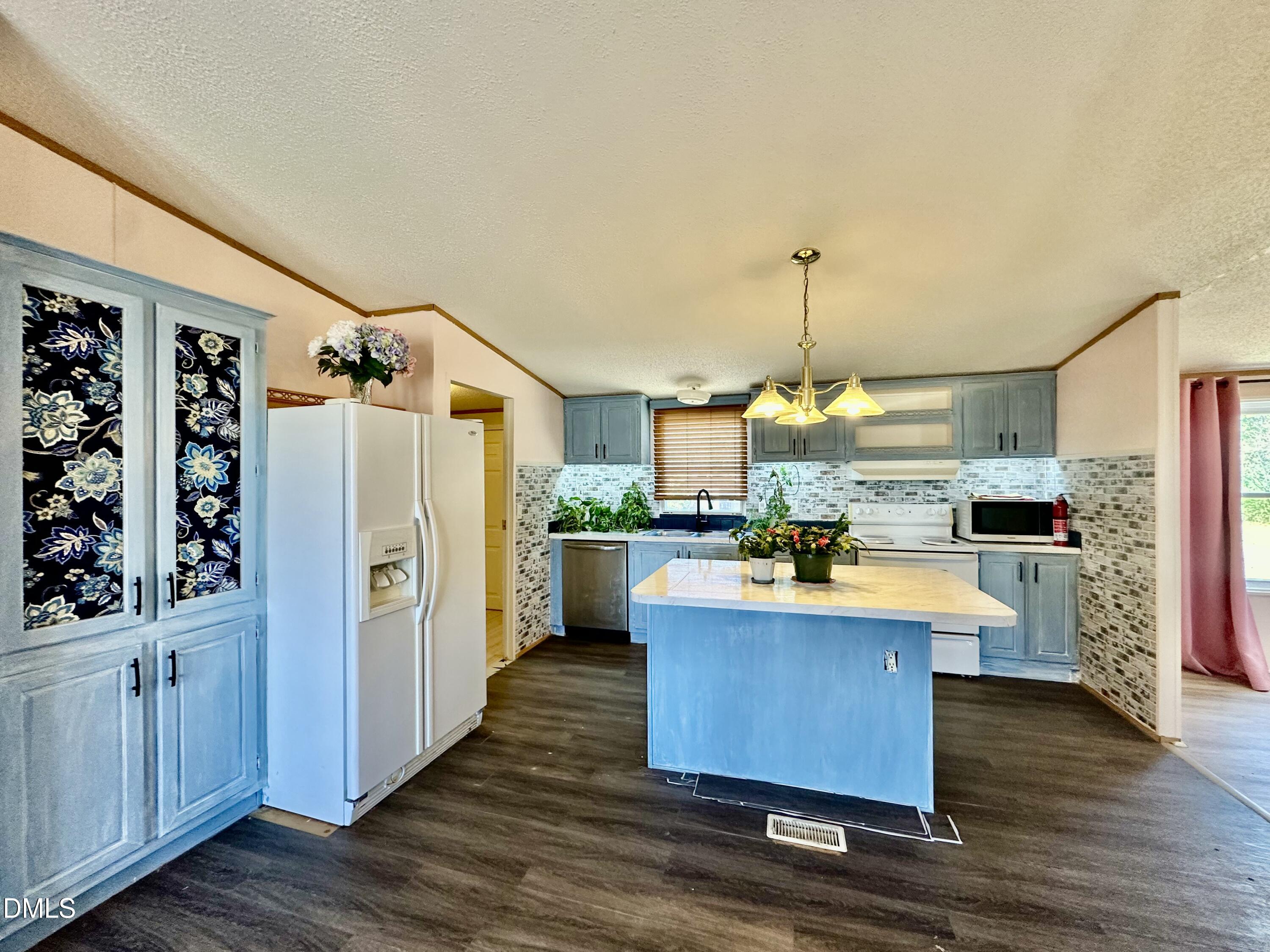 287 Oliver Loop Road Roxboro, NC 27574 - Photo 9 of 26 a large kitchen with stainless steel appliances kitchen island granite countertop a table chairs and a refrigerator