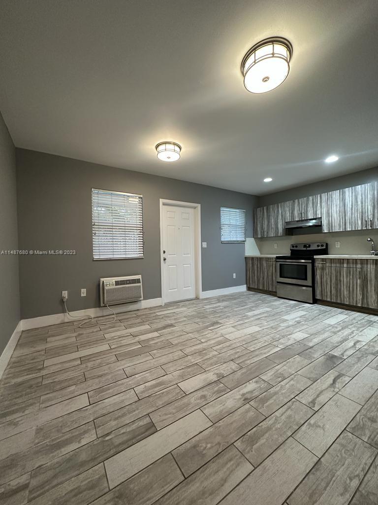 a view of an empty room and a kitchen