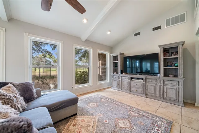 a living room with furniture a flat screen tv and floor to ceiling window