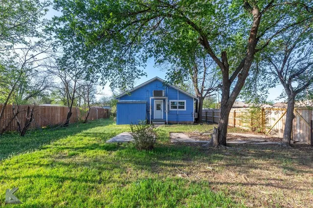 a view of a yard in front of a house with large trees