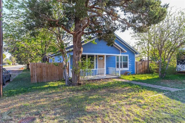 a front view of a house with a yard and tree
