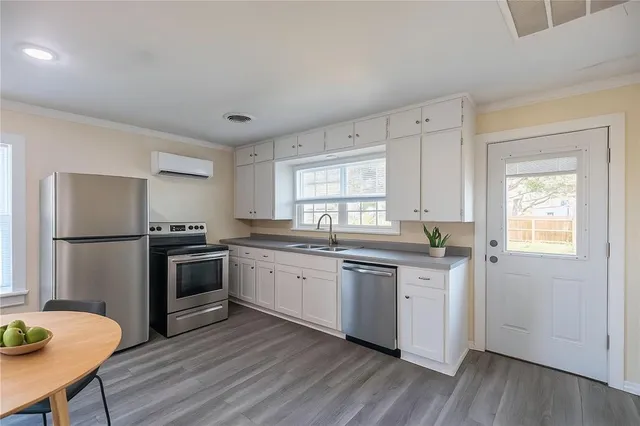 a kitchen with stainless steel appliances granite countertop a stove a sink dishwasher a refrigerator with a dining table and wooden floor