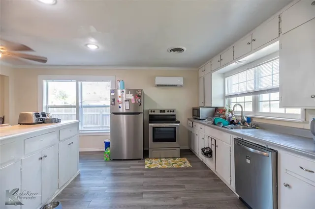 a kitchen that has a lot of cabinets in it and wooden floors
