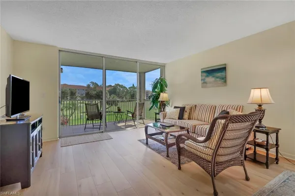 a living room with furniture a flat screen tv and a floor to ceiling window