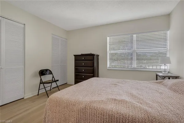 a bedroom with a bed and chair with a large window