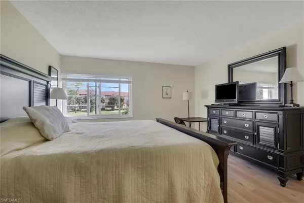 a bedroom with a bed and a flat tv screen on a dresser
