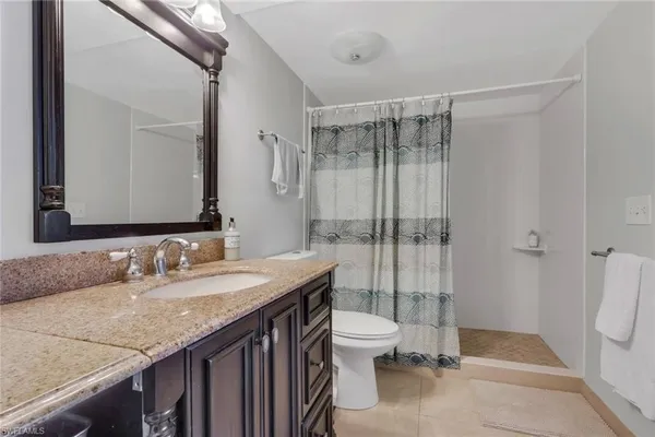 a bathroom with a granite countertop sink toilet and shower