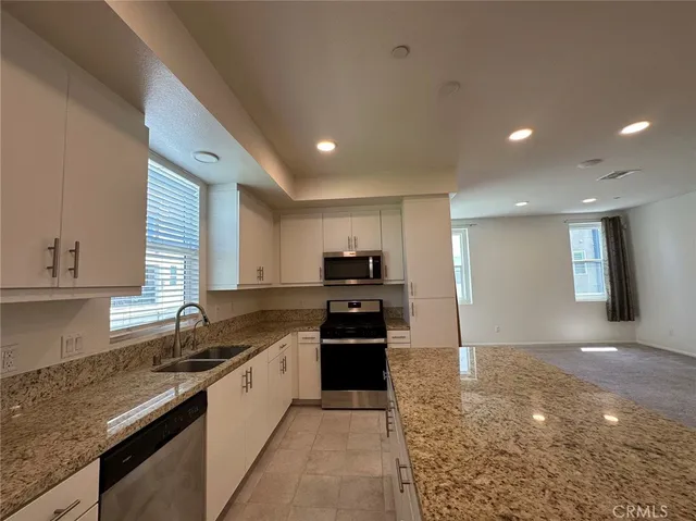 a kitchen with granite countertop a refrigerator and a stove top oven