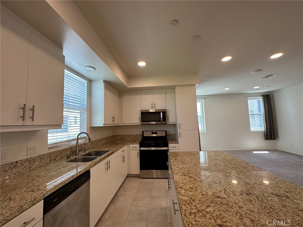 10517 Huxley Drive Rancho Cucamonga, CA 91730 - Photo 3 of 16 a kitchen with granite countertop a refrigerator and a stove top oven
