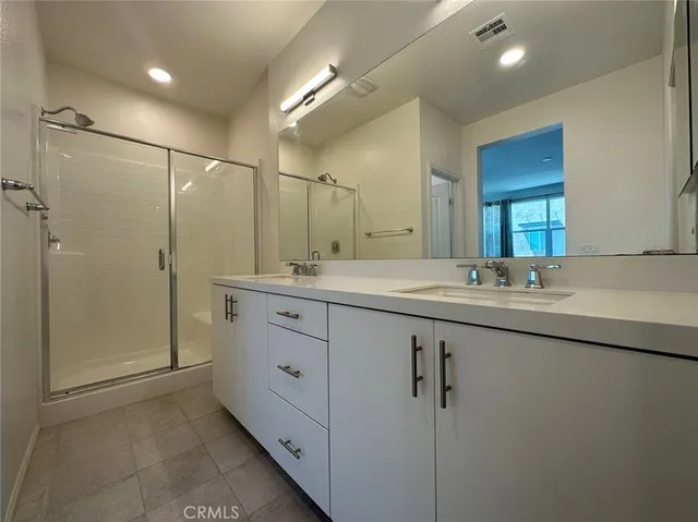 a bathroom with a double vanity sink mirror and shower