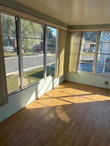 a view of an empty room with a floor to ceiling window and wooden floor
