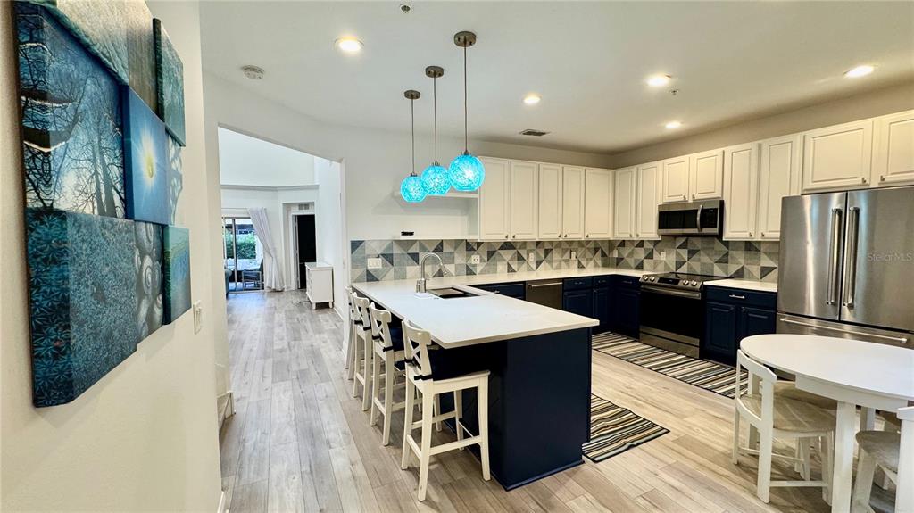 6826 Sorrento Street Orlando, FL 32819 - Photo 3 of 28 a kitchen with a refrigerator a stove top oven a sink dishwasher and white cabinets with wooden floor