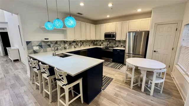 a kitchen with stainless steel appliances a table chairs and a refrigerator