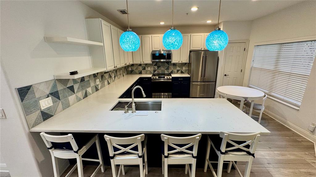 6826 Sorrento Street Orlando, FL 32819 - Photo 5 of 28 a kitchen with stainless steel appliances a dining table chairs and a wooden floor