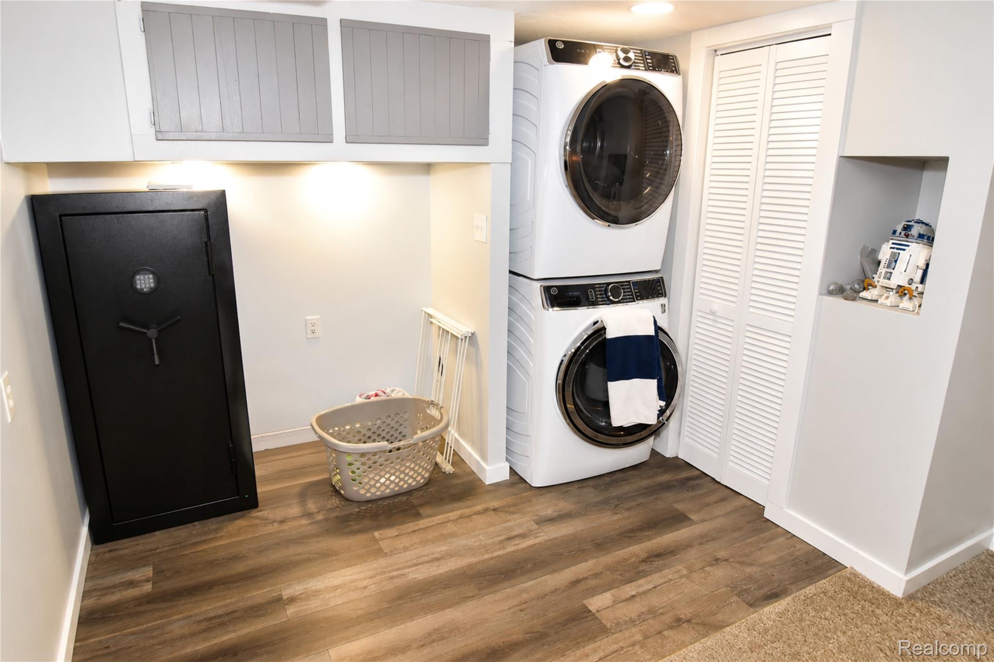 1405 Middle Road Highland, MI 48357 - Photo 16 of 18 Dedicated laundry area featuring wood-finish flooring, a stacked washer and dryer, white louvered bifold doors, and recessed overhead lighting