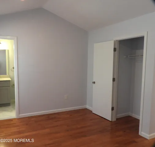 a view of an empty room with wooden floor and closet