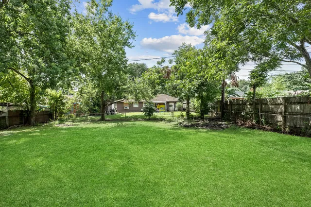 a view of a house with a big yard potted plants and large trees