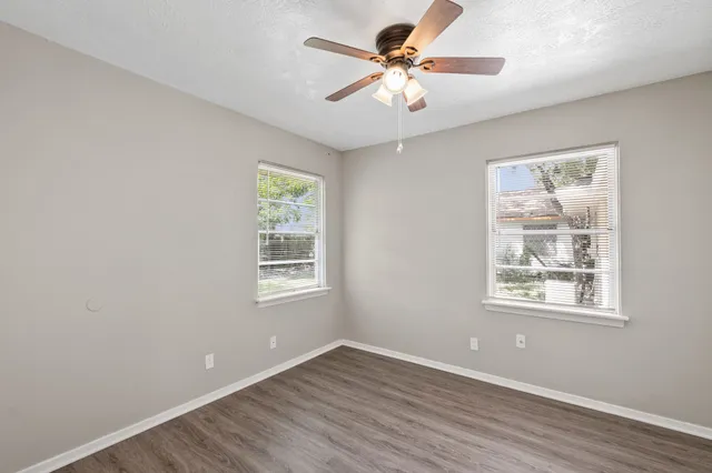 a view of an empty room with a window and wooden floor