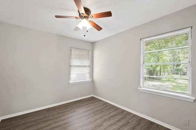 a view of an empty room with wooden floor and a window