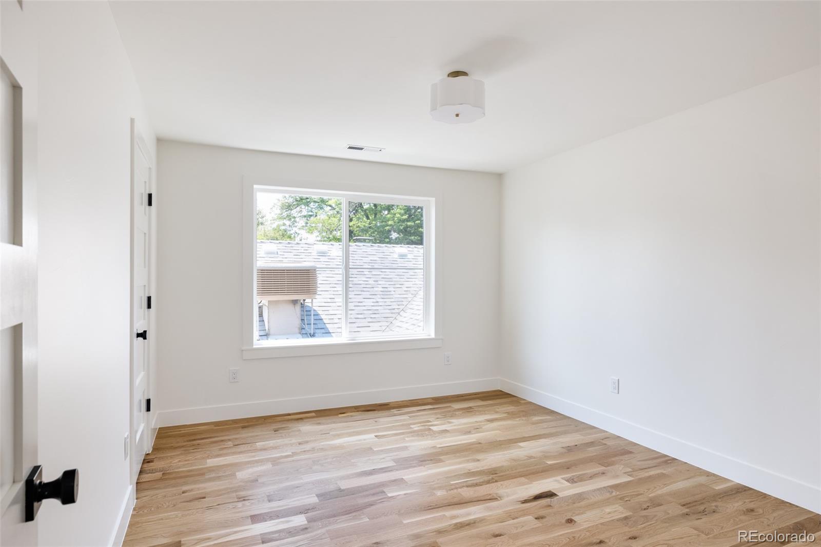 832 Adams Street Denver, CO 80206 - Photo 24 of 39 an empty room with wooden floor and windows