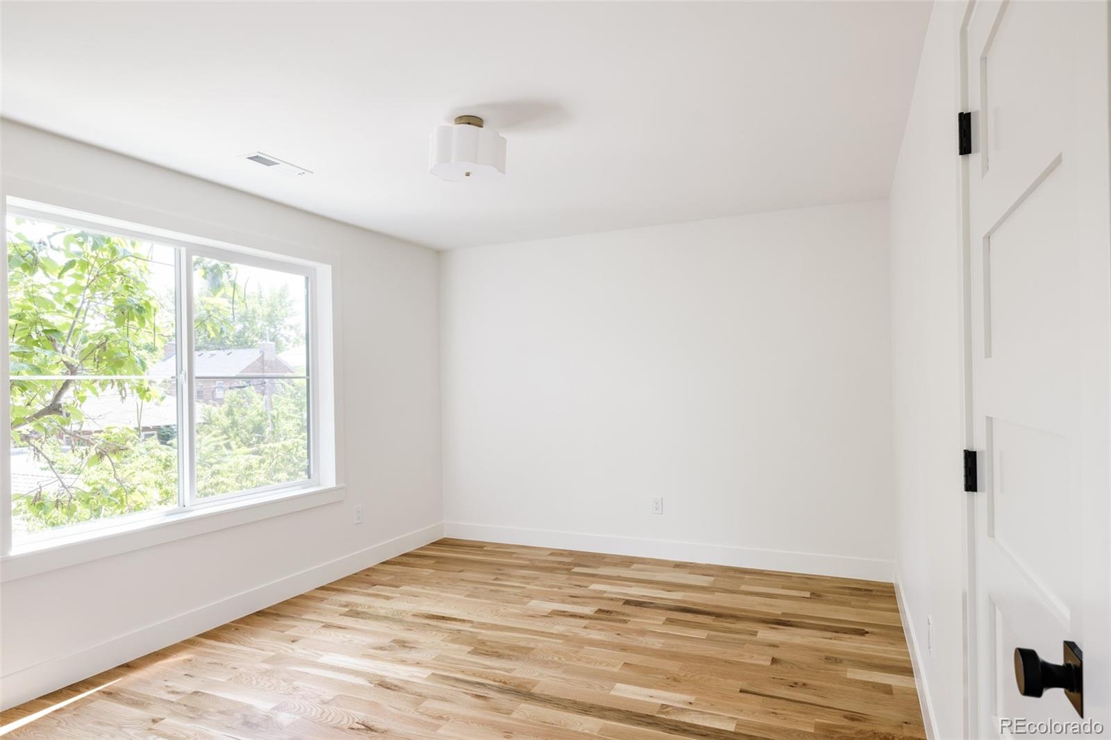 832 Adams Street Denver, CO 80206 - Photo 26 of 39 a view of an empty room with wooden floor and a window