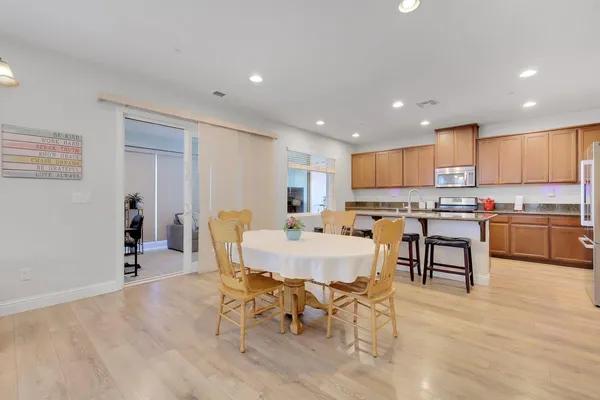 a view of kitchen with granite countertop refrigerator cabinets dining table and chairs
