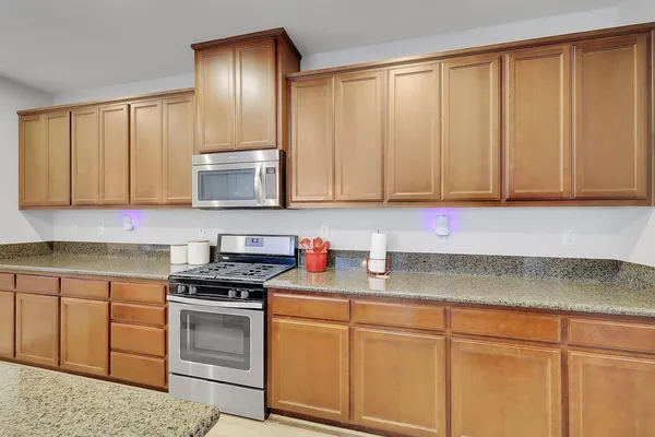 a kitchen with stainless steel appliances granite countertop a refrigerator oven stove a sink a dining table and chairs with wooden floor