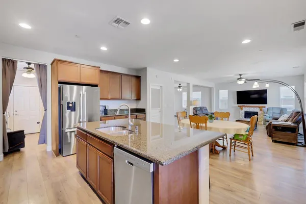 a kitchen with stainless steel appliances granite countertop a refrigerator a stove and a sink with wooden floor