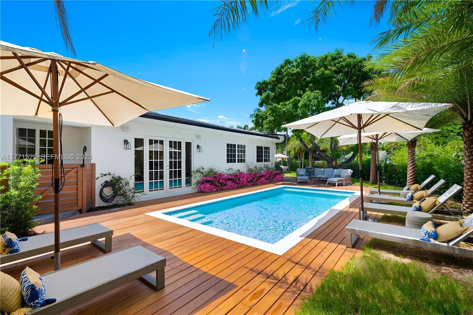 2575 Pine Tree Drive Miami Beach, FL 33140 - Photo 35 of 36 a view of pool with lawn chairs under an umbrella