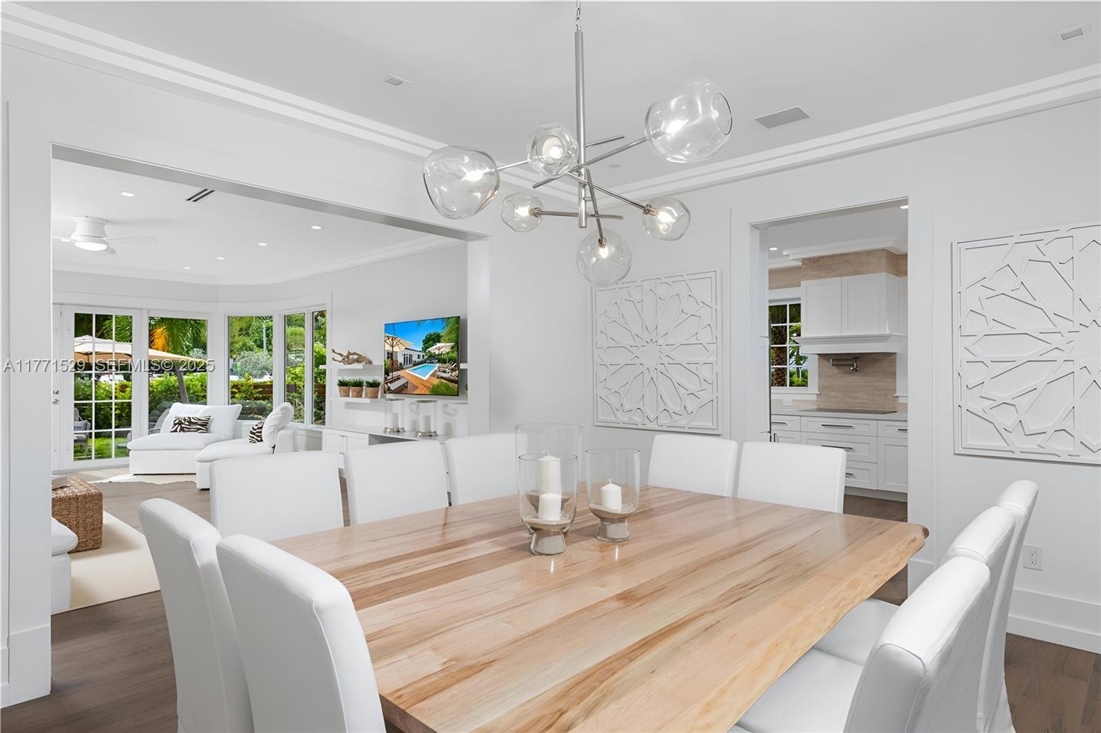 2575 Pine Tree Drive Miami Beach, FL 33140 - Photo 5 of 36 a dining room with wooden floor a chandelier a wooden table and chairs