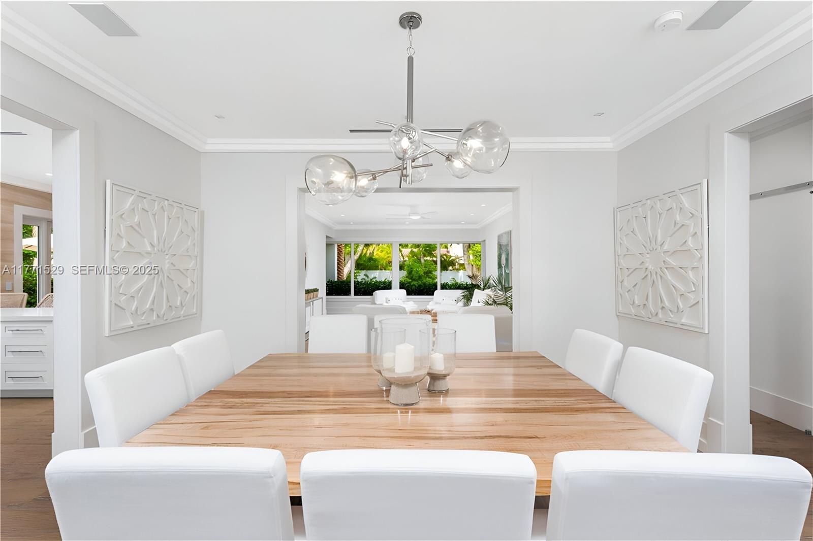 2575 Pine Tree Drive Miami Beach, FL 33140 - Photo 6 of 36 a view of a dining room with furniture a chandelier and wooden floor
