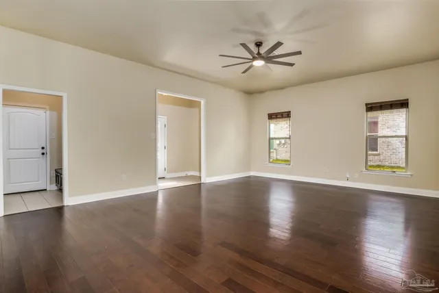 a view of an empty room with wooden floor and window