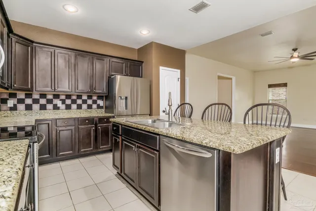 a kitchen with stainless steel appliances kitchen island granite countertop a table and a refrigerator