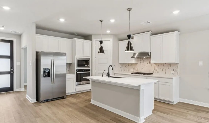 212 Raine Manor Montgomery, TX 77316 - Photo 1 of 12 a kitchen with kitchen island white cabinets and stainless steel appliances