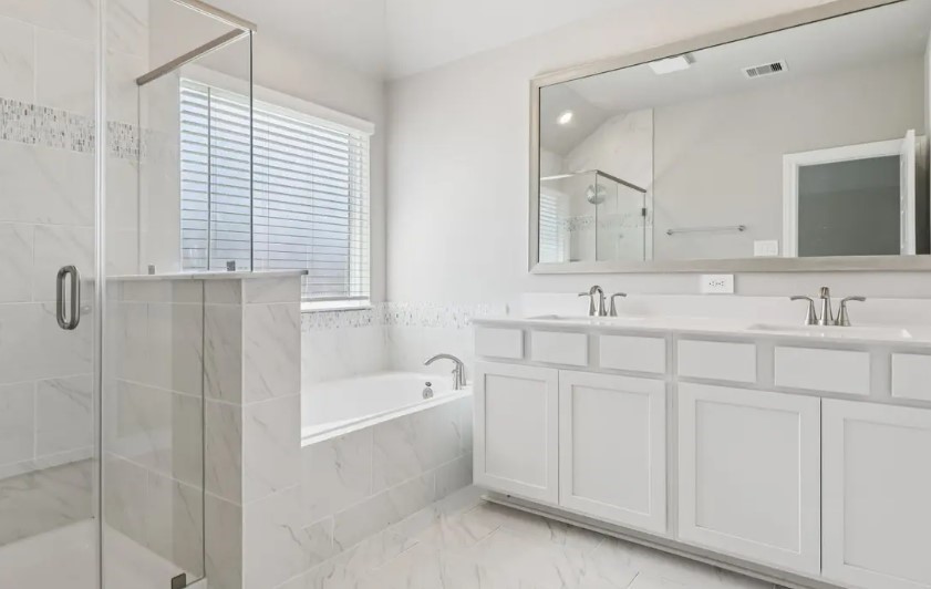 212 Raine Manor Montgomery, TX 77316 - Photo 5 of 12 a bathroom with a double vanity sink a mirror and a bathtub